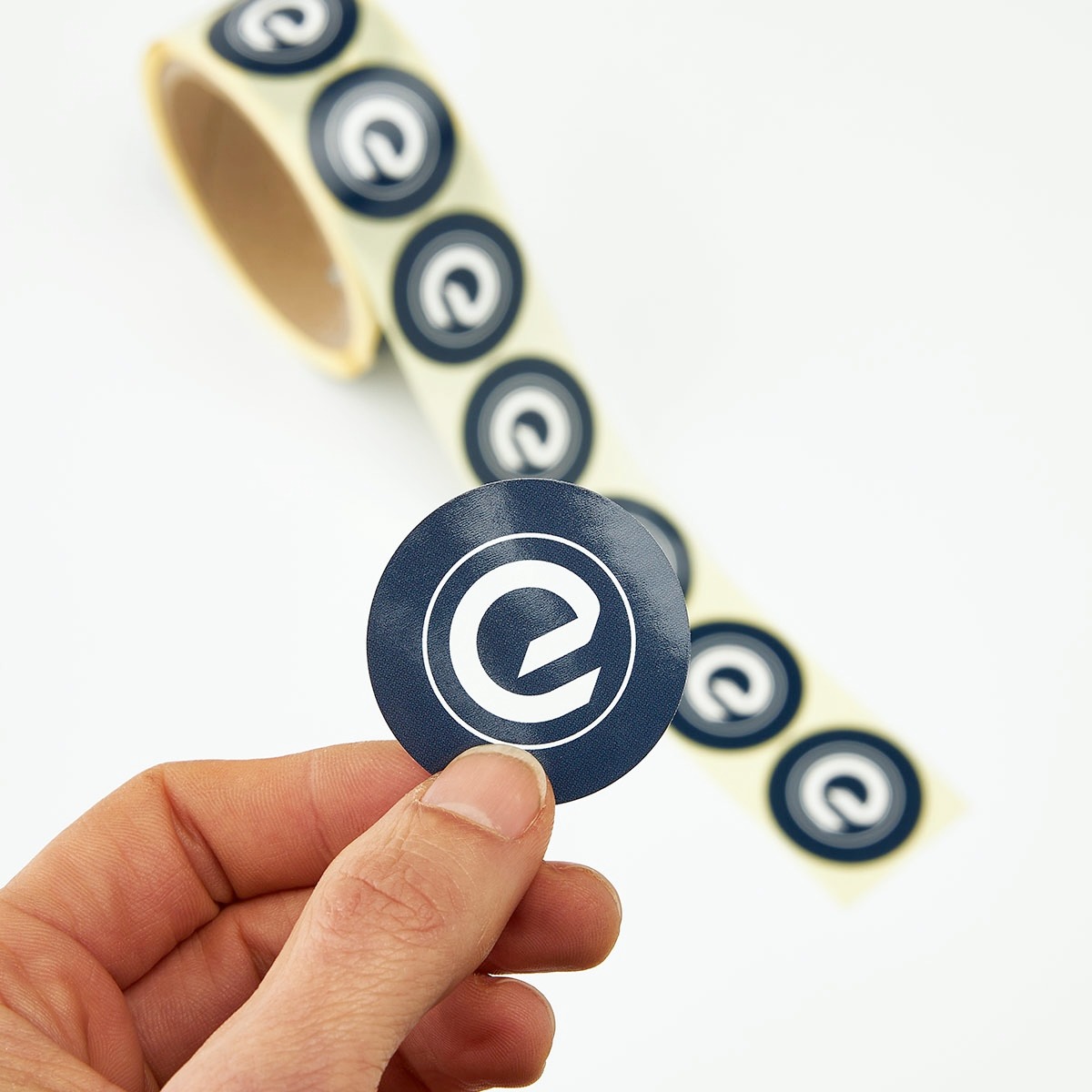 logo stickers op rol, met een logo sticker vast in de hand
